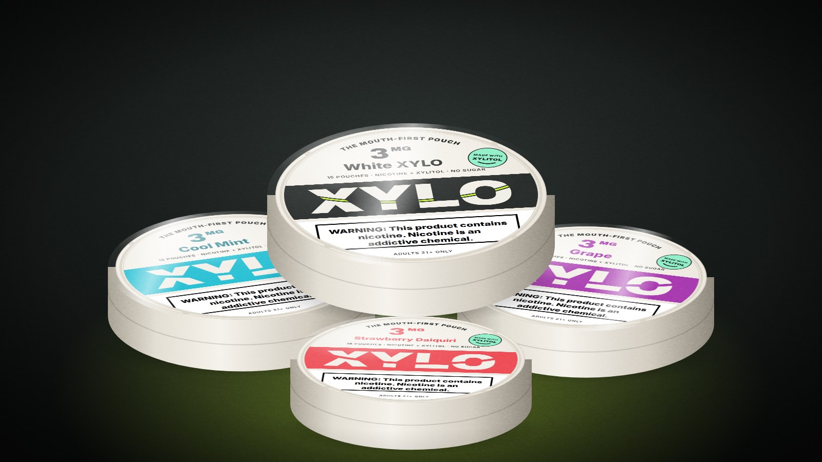 Four revamped XYLO cans rendered in 3D under a spotlight: White XYLO, Cool Mint, Grape and Strawberry Daiquiri